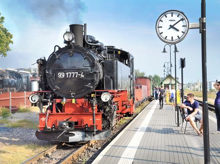 Eine Dampflok in Schwarz-Rot fährt im Bahnhof in Radebeul ein