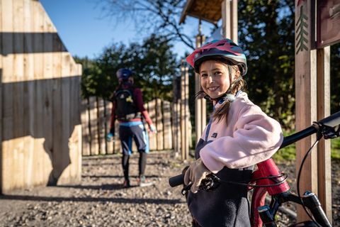 Ein Mädchen steht neben ihrem Mountainbike und lächelt.