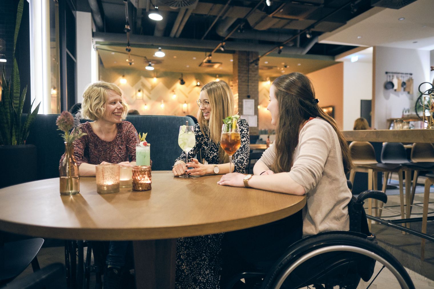 Drei Frauen mit Cocktails sitzen an einem Tisch in der Hotelbar Indigo Dresden