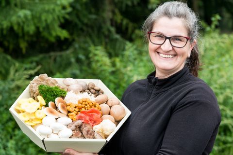 Eine Frau hält eine Schüssel mit Pilzen in der Hand. Sie verkauft Müntzners Gourmetpilze.