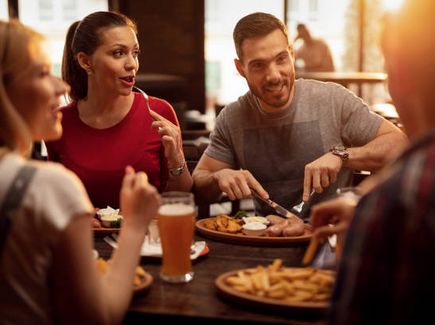 Gruppe sitzt gemütlich zum essen in einem Restaurant zusammen.