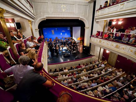 Eine gut besuchte Veranstaltung, auf der Bühne stehen Musiker mit ihren Instrumenten.