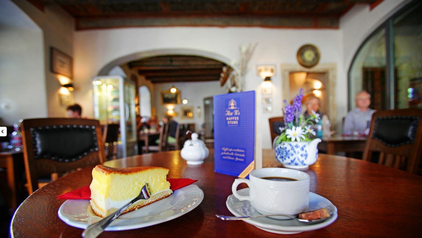 Auf einem Tisch in Ilses Kaffeestube stehen eine Eierschecke und eine Tasse Kaffee. Die Kaffeestube ist im Tom Pauls Theater in Pirna. 