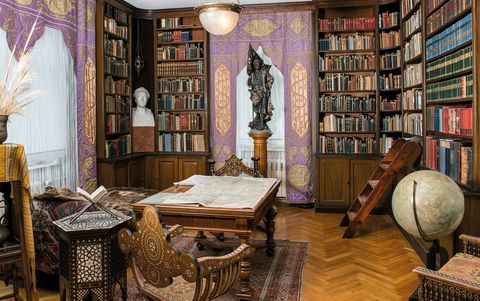 Bibliothek mit Bücherregalen die bis zur Decke ragen und einem Schreibtisch im Zentrum
