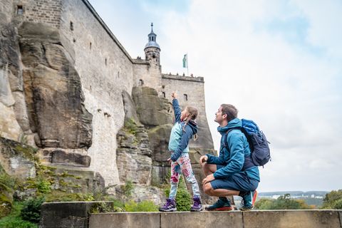 Ein Vater steht mit seiner Tochter am Fuße der Festung Königstein.