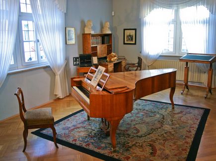 Zimmer mit einem Klavier und antiken Möbelstücken