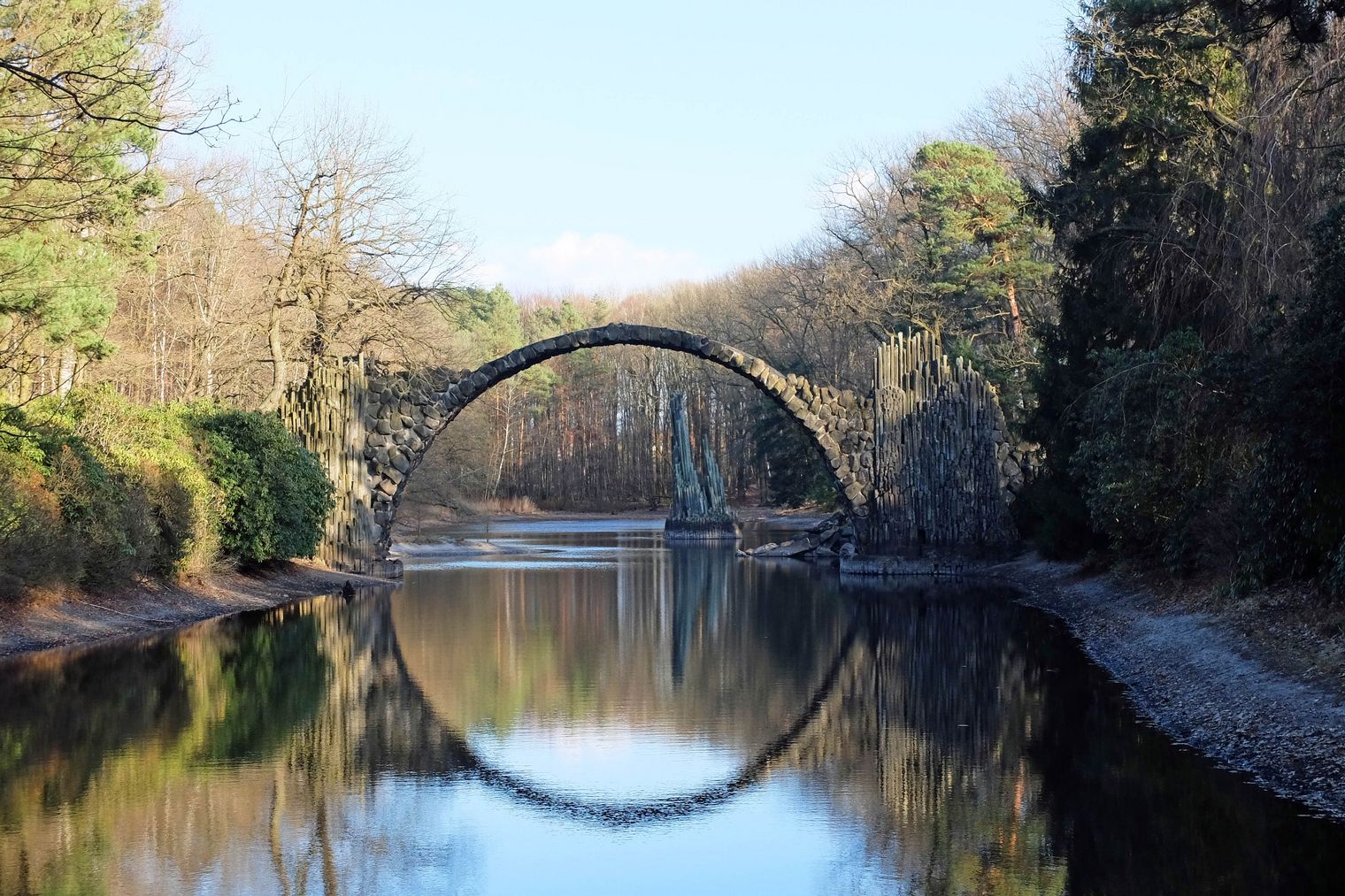 Die Rakotzbrücke spannt sich über einen Teich im Rhododendronpark Kromlau und spiegelt sich im Wasser. 