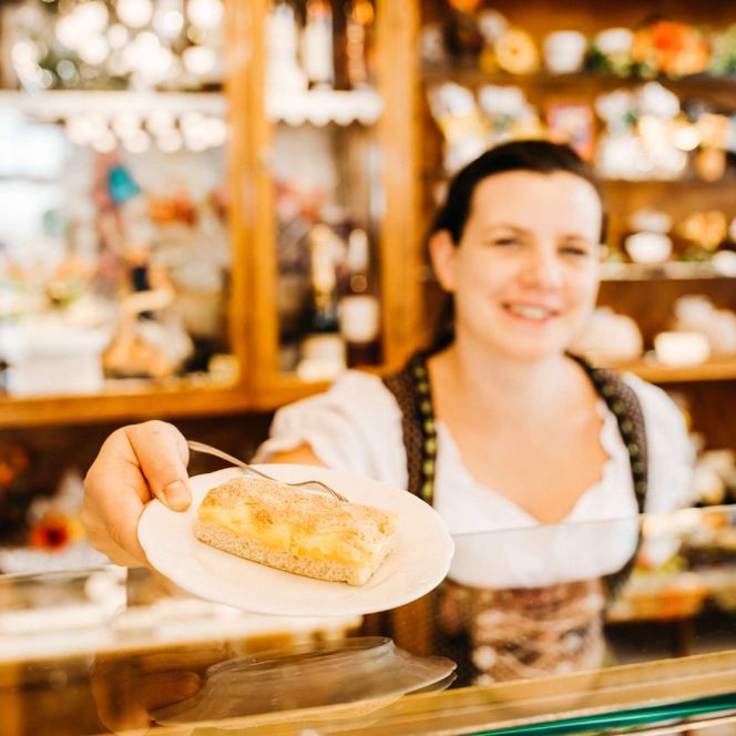 Bäckerin gibt ein Stück Freiberger Eierschecke über die Ladentheke