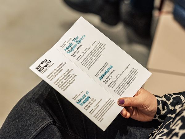 Flyer THEATER DER WELT in der Hand einer Frau