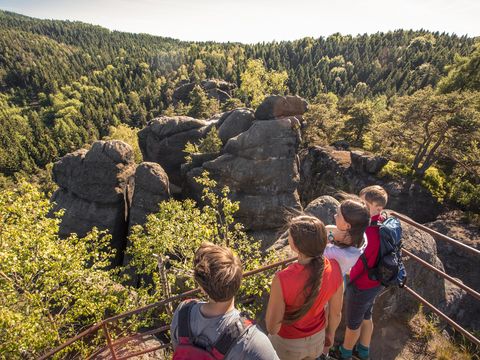 Eine Familie steht an einem Aussichtspunkt bei Jonsdorf. Sie schauen auf die Natur im Zittauer Gebirge. 