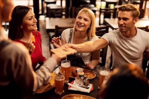 Gruppe sitzt zusammen und stößt mit einem Bier an.