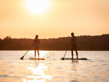 Zwei Personen beim Stand-Up-Paddling auf einem See