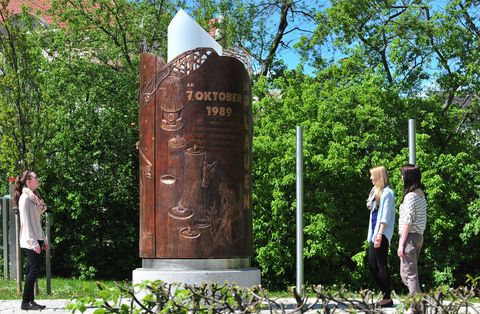 Das Wende-Denkmal hat die Form einer Kerze. Sie besteht aus einer von innen beleuteten Acryl-Stele und wird umschlossen von einem dreiteiligen Bronzemantel.