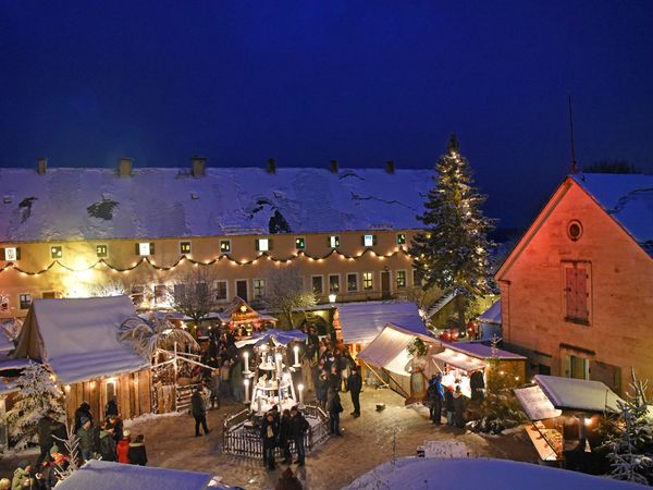 Weihnachtsmarkt Festung Königstein Blick auf die Marktbuden auf dem Paradeplatz; vorn die drei Meter hohe Erzgebirgische Weihnachtspyramide, hinten die Alte Kaserne mit dem längsten Adventskalender Deutschlands.