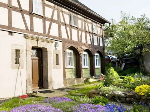 Umgebindehaus im Zittauer Gebirge, davor blühen Blumen im Garten 