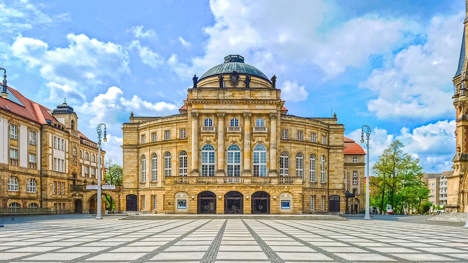 Opernhaus Chemnitz bei Tag mit großer Kuppel und hellem Platz davor. / Chemnitz Opera House in daylight with large dome and open square in front.