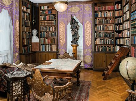 Bibliothek mit Bücherregalen die bis zur Decke ragen und einem Schreibtisch im Zentrum