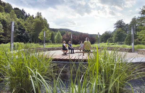 Vier Personen sitzen in einem Kurpark und meditieren