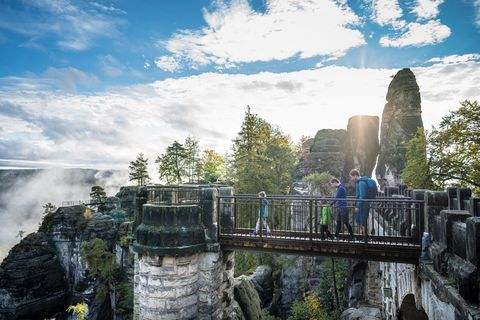 Eine Familie steht auf der Basteibrücke und betrachtet die Umgebung.