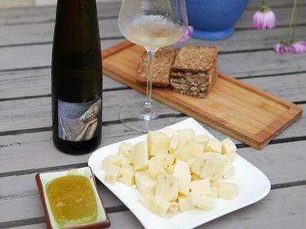 Eine Flasche Wein auf einem Tisch und dazu gibt es Brot und Käse