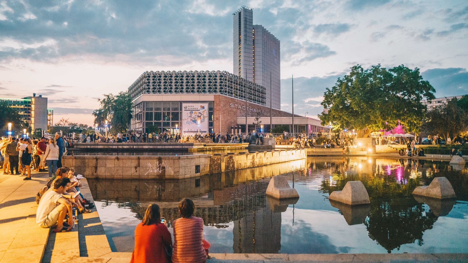 Vorplatz Stadthalle Chemnitz im Abendlicht, reges Treiben - junge Menschen verweilen im Sommer. 