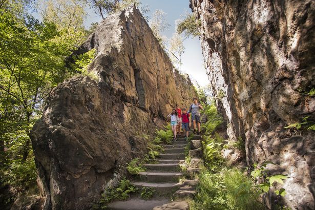 Eine Familie wandert zwischen zwei Felsen hindurch. Sie ist auf dem Oberlausitzer Bergweg im Zittauer Gebirge.