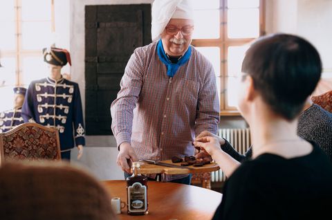 Gästen werden Speisen auf einem Holzbrett serviert.