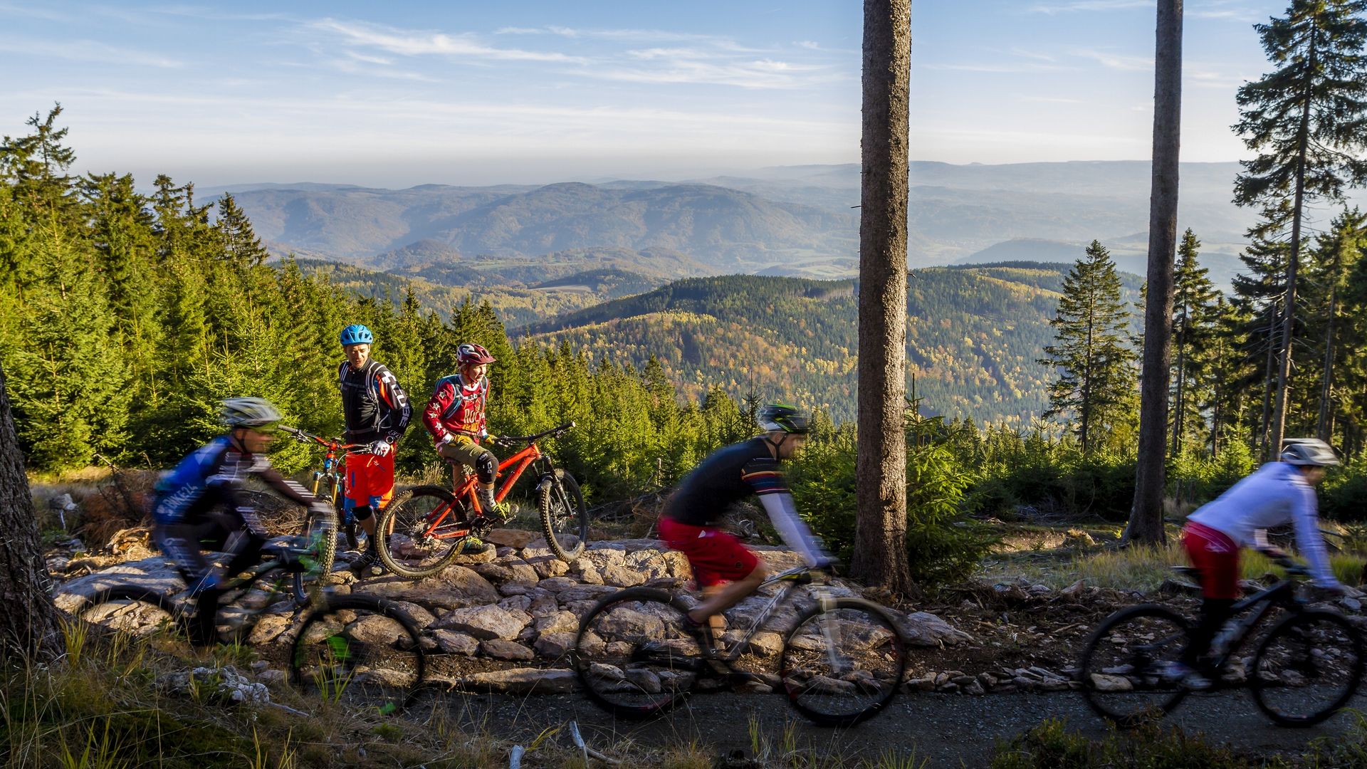Biker fahren im Trail Park in Klinovec mit Blick auf den Egergraben und auf das Duppauer Gebirge