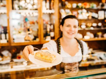 Eine Frau hält ein Stück Kuchen über einen Tresen. Die Freiberger Eierschecke ist eine Spezialität. 