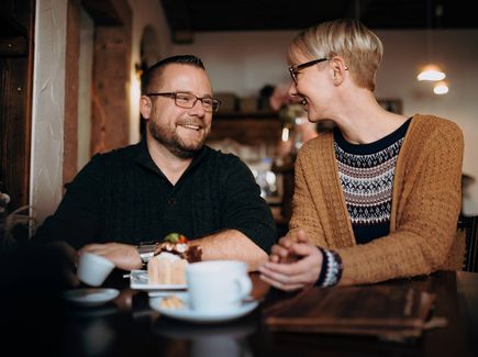 Pärchen an einem Tisch mit Kaffee und leckerem Kuchen