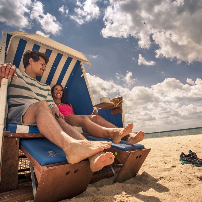 Eine Frau und ein Mann sitzen in einem Strandkorb am Bärwalder See. Sie machen Urlaub im Lausitzer Neuseenland.