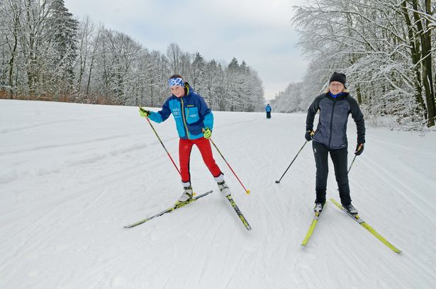 Mutter und Tochter machen gemeinsam Langlauf im verschneiten Winterwald