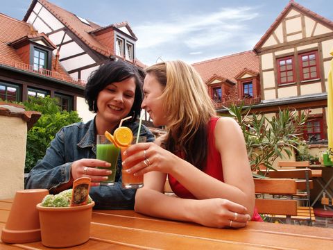 Zwei Frauen sitzen im Biergarten und stoßen an.