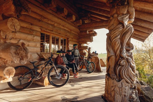 A family with two children sitting on the terrace of a wooden house. They are taking a break on the Blockline trail.
