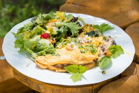 Ein Wildkräuteromelette mit Salat ist auf einem Teller angerichtet. Er steht in der Kräuterbude in Saupsdorf. 