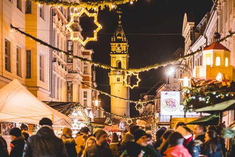 Menschen sind auf einem Weihnachtsmarkt in Bautzen. Sie sind auf dem Wenzelsmarkt, der weihnachtlich geschmückt ist. 