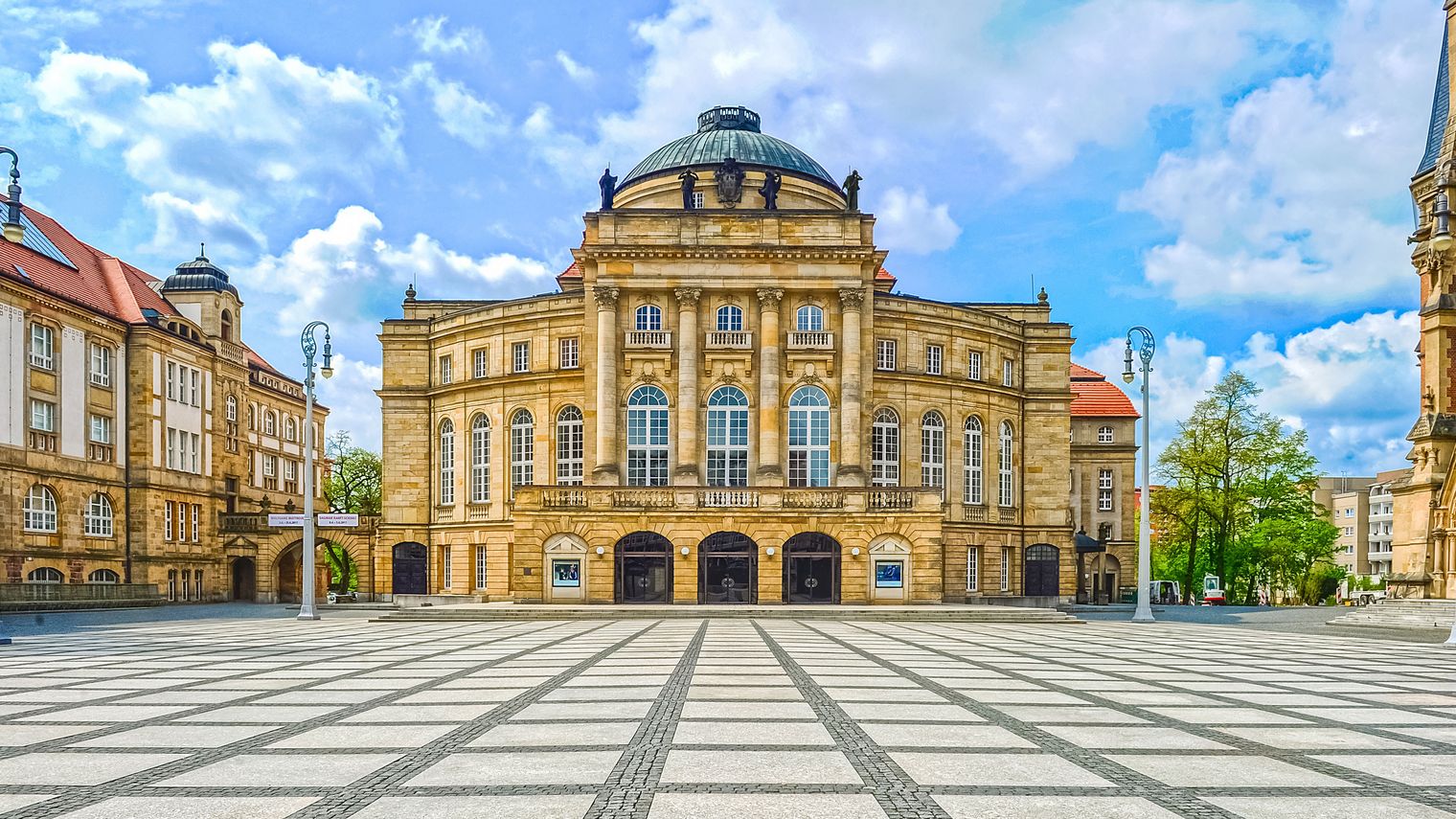 Opernhaus Chemnitz bei Tag mit großer Kuppel und hellem Platz davor. / Chemnitz Opera House in daylight with large dome and open square in front.