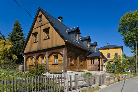Ein braunes Umgebindehaus aus Holz steht an einer Straße in Hinterhermsdorf.
