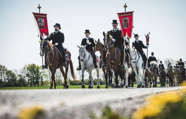 Männer mit Hüten und Wappen reiten auf Pferden durch Bautzen. Der Osterritt ist eine sorbische Tradition. 