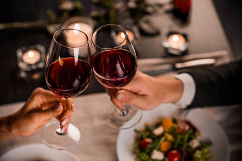Pärchen stößt mit einem Glas Wein beim Abendessen an.