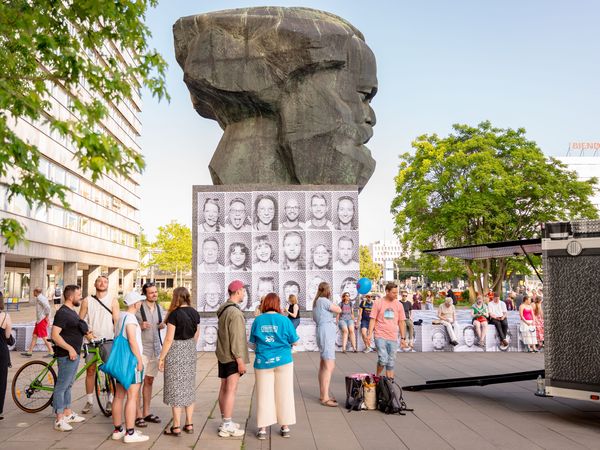 Menschen stehen zum KOSMOS Festival in Chemnitz vor dem Karl-Marx-Kopf