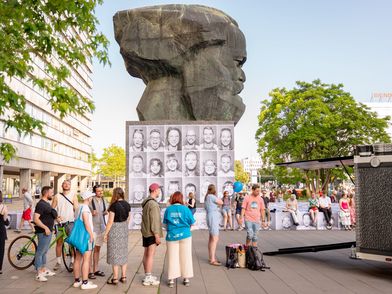 Menschen stehen zum KOSMOS Festival in Chemnitz vor dem Karl-Marx-Kopf