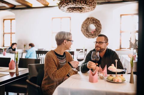 Pärchen sitzt mit einem Glas Wein im Restaurant und stößt an