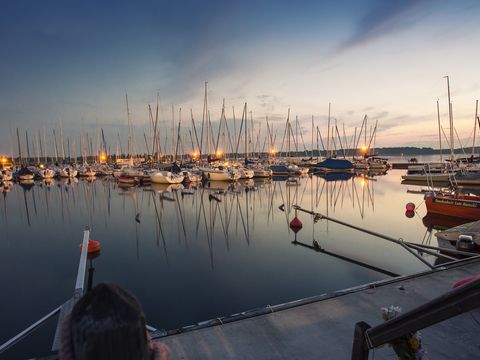 Ein Steg am Cospudener See bei Abenddämmerung mit zahlreichen Booten.