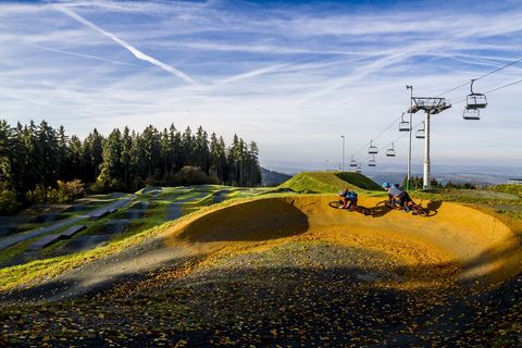 Zwei Mountainbiker fahren mit ihren Rädern in eine Kurve. Sie sind in der Bikewelt Schöneck im Vogtland.