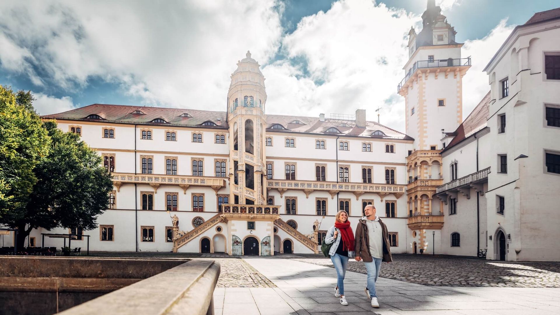 Ein Paar vor Schloss Hartenfels in Torgau im Sonnenschein / A couple in front of Hartenfels Castle in Torgau in the sunshine