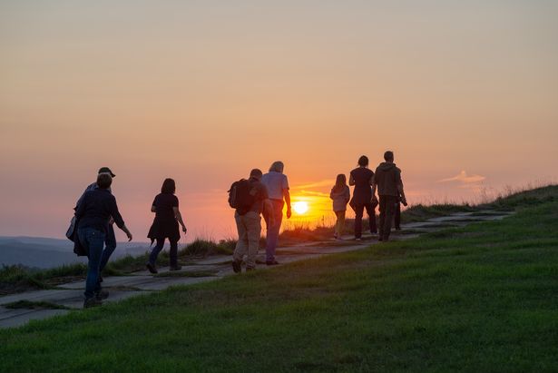 Eine Gruppe macht eine Wanderung in Pobershau. Sie wandern der Sonne entgegen. 