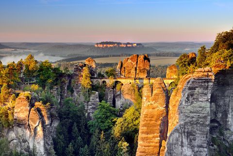 Die Sandsteinfelsen der Bastei im Nationalpark Sächsische Schweiz glänzen im Abendlicht. In der Mitte ist die berühmte Basteibrücke.