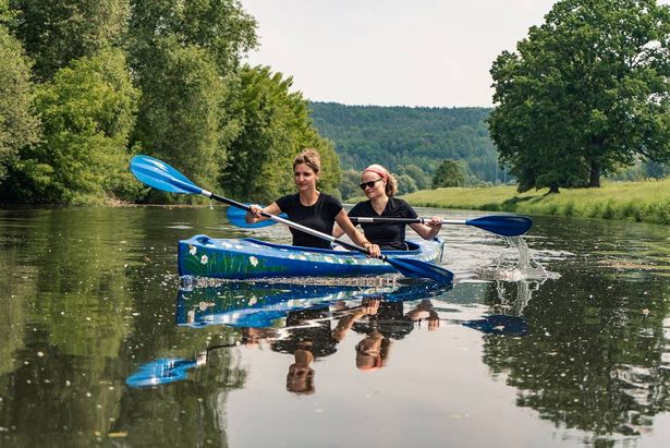 Zwei Frauen paddeln Fluss entlang