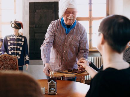 Gästen werden Speisen auf einem Holzbrett serviert.